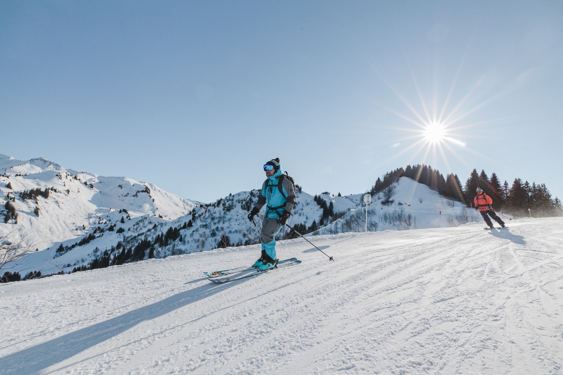 Skieur dévalant une pente enneigée avec vue sur les montagnes des Gets